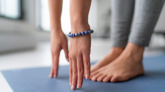 Yoga at home exercise in living room house - woman on fitness mat training stretching legs touching toes.
